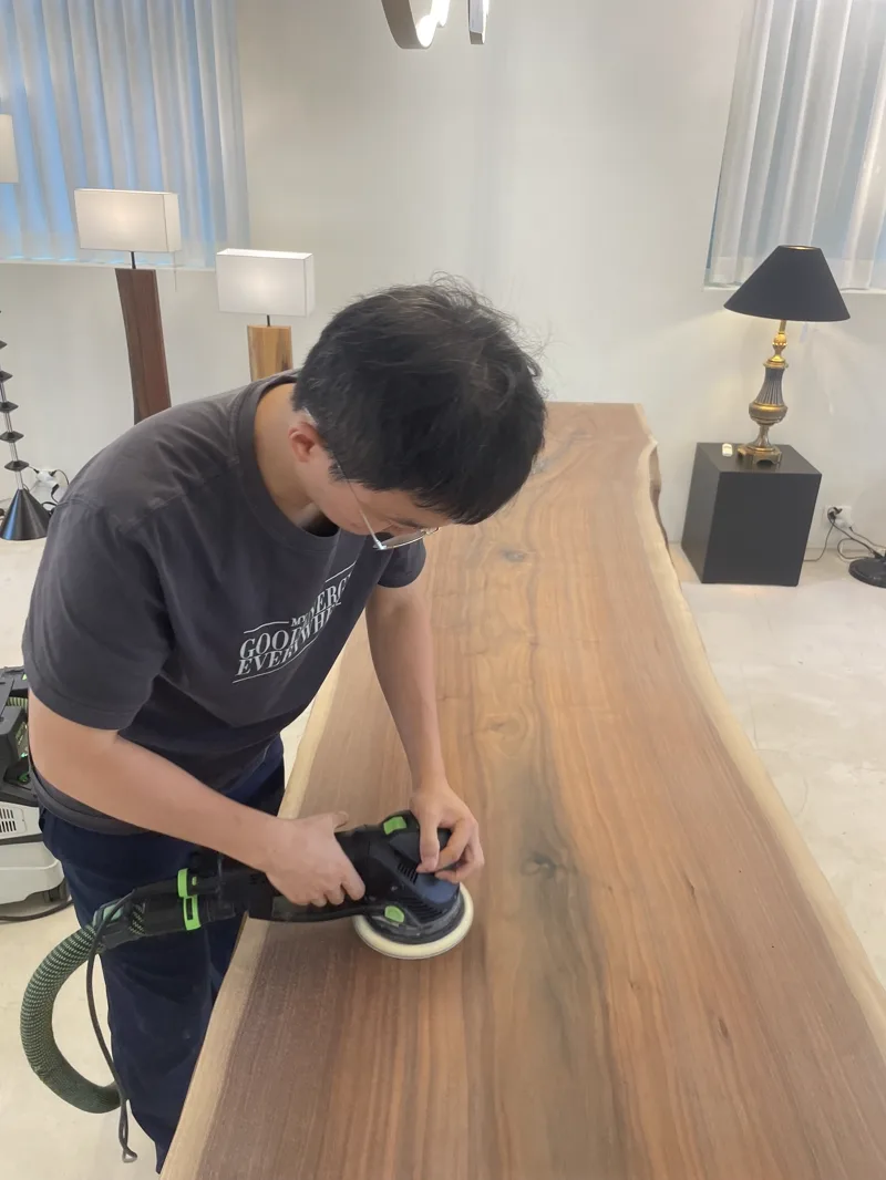 백곰홈닥터 대표가 집진 샌더로 우드슬랩 테이블을 샌딩하는 모습